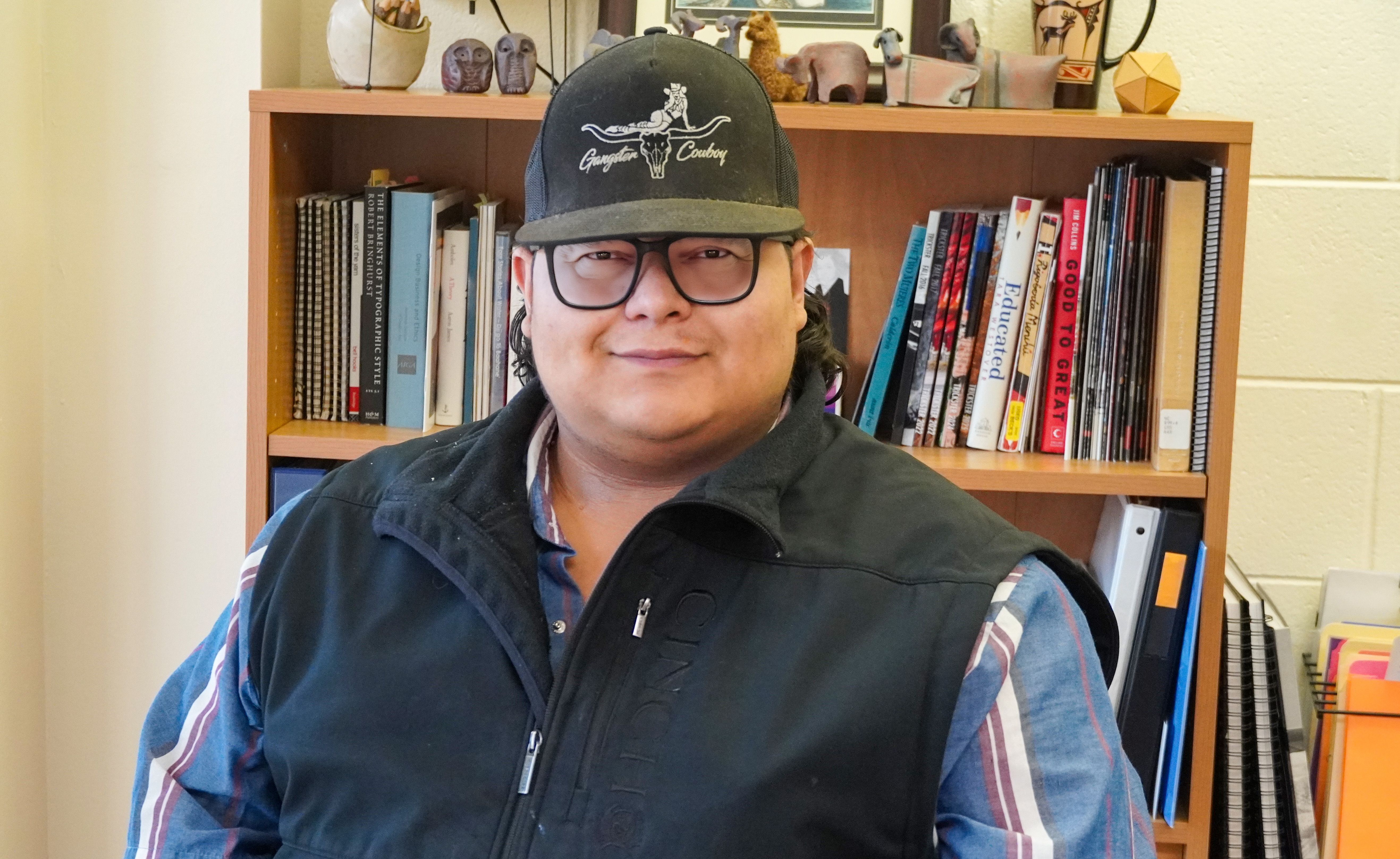 Matt Baldonado wearing dark-rimmed glasses, a baseball cap reading 